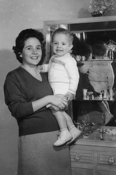 Vintage black and white image taken in the 60s of a young woman posing with her toddler son child stock photo