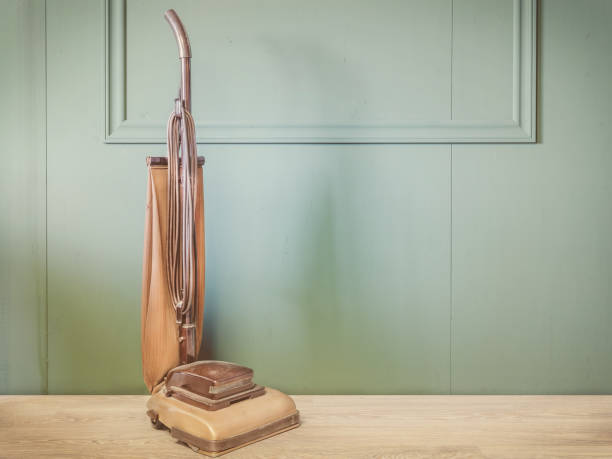 Vintage brown vacuum cleaner in an empty room with green wall and wooden floor stock photo