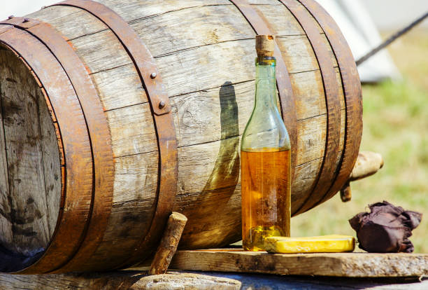 vintage cider barrrel with bottle on table Closeup of vintage wooden barrrel and cider bottle on table at outdoor calvados stock pictures, royalty-free photos & images