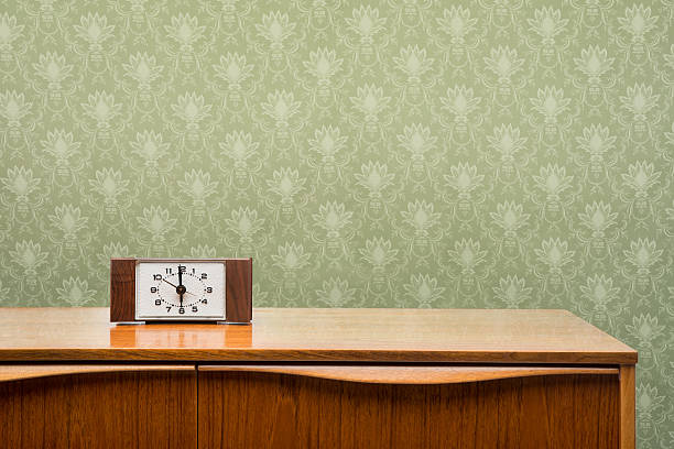 Vintage Clock On Dresser Bluish vintage clock from the 1950's to 1960's sitting on a mid-century modern dresser against a vintage pattern wallpaper. dresser photos stock pictures, royalty-free photos & images