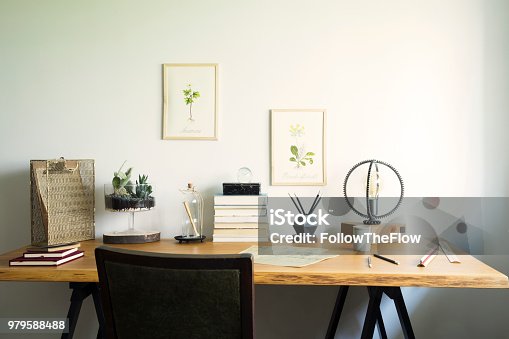 istock Vintage, creative home office interior with wooden desk, books, laptop, romantic illustrations of plants, lamp and office accessories. 979588488