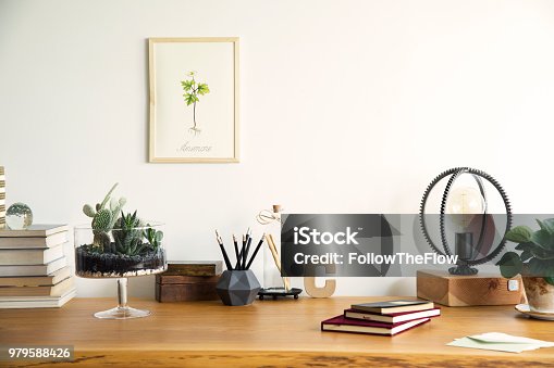 istock Vintage, creative home office interior with wooden desk, books, notebooks, romantic illustrations of plants, table lamp and office accessories. Stylish space for freelancer. 979588426