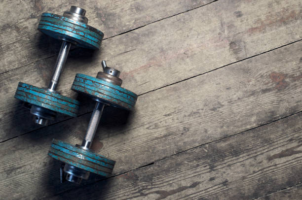 Vintage dumbbells on the wooden floor Vintage dumbbells on the wooden floor. Top view . Flat lay. Oldschool. Vintage.  With copy space dumbells stock pictures, royalty-free photos & images