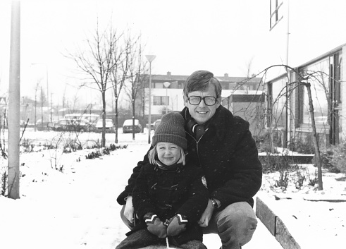 1978 vintage, seventies, retro monochrome portrait of father and daughter in winter snow setting in a suburban area.