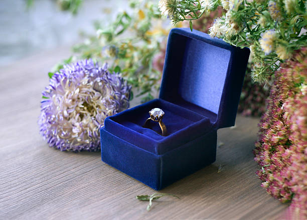 Vintage gold diamond engagement ring in blue velvet box Still life with gold diamond engagement ring in blue velvet box and garden flowers. wedding ring box stock pictures, royalty-free photos & images