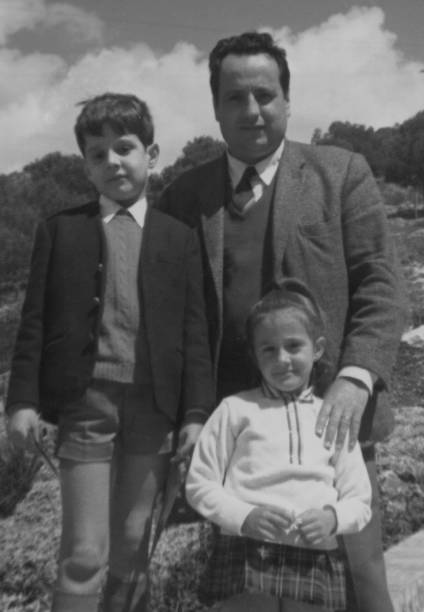 Vintage image from the 60s, mid adult man posing with his children looking at the camera stock photo