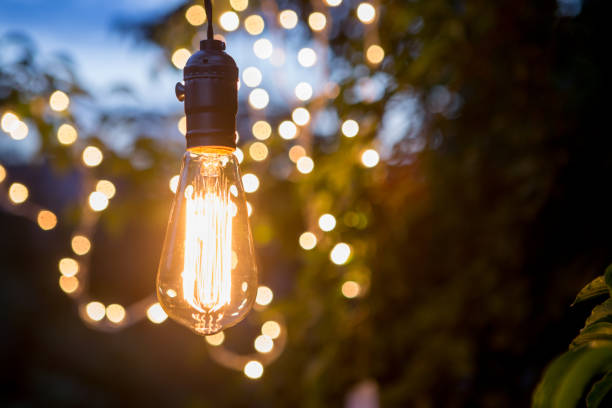 Vintage incandescent bulb and party lights in a garden, summertime party stock photo