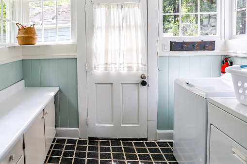 A vintage laundry room filled with windows and natural light and a washer and dryer and folding table
