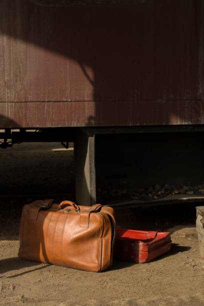 Vintage luggage bags placed in front of an old brick wall with a retro window and cargo train cabin stock photo