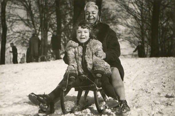 Vintage photo of mother and daughter sledding stock photo