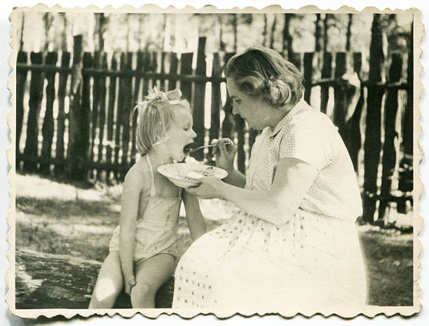 Vintage photo of mother feeding her daughter stock photo