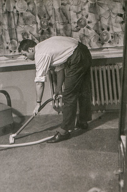 Vintage photo of young man vacuuming (circa 1960) stock photo