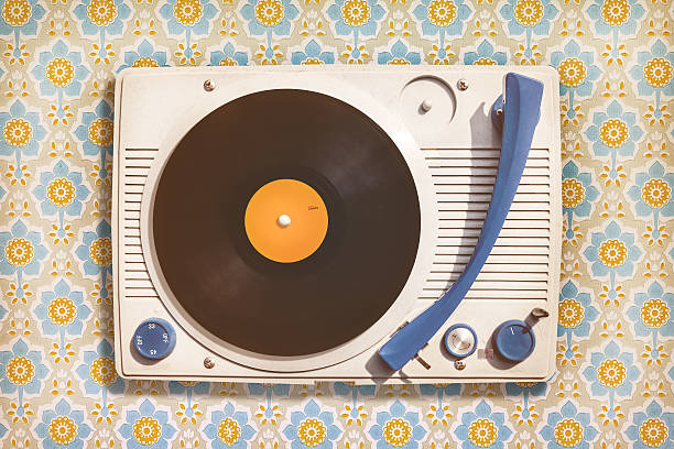 Vintage record player on top of flower wallpaper Retro styled image of an old record player on top of flower wallpaper turntable stock pictures, royalty-free photos & images