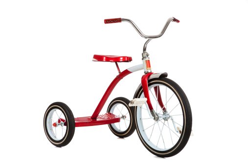 A red toy tricycle on a white background with copy space