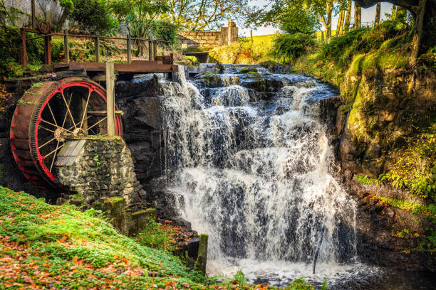 Vintage red waterwheel with waterfall in Glenariff Forest Park Vintage red waterwheel with waterfall in autumn colours in Glenariff Forest Park, Count Antrim, Northern Ireland water wheel stock pictures, royalty-free photos & images