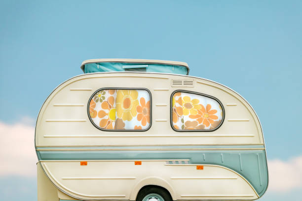 Vintage seventies white caravan in front of a blue sky with clouds stock photo