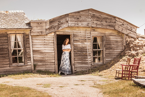 Vintage style woman leaning in doorway of old prairie homestead