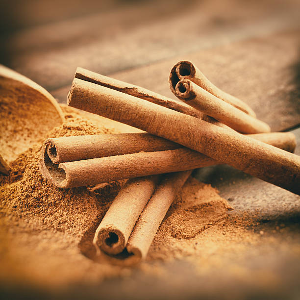 Vintage stylized photo of Cinnamon sticks and powder Vintage stylized photo of Cinnamon sticks and cinnamon powder on wooden plank cinnamon stock pictures, royalty-free photos & images
