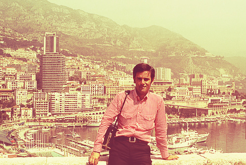 Vintage image from the seventies featuring a man standing against a view of the city of Cannes behind him.