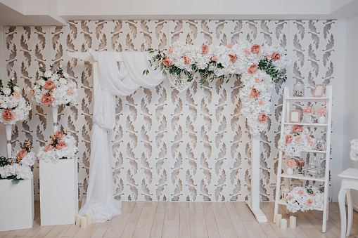 Vintage wedding party photo booth zone decorated with white roses in vases, and old white table