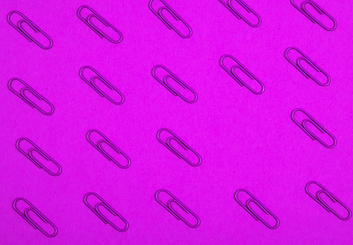 Top view of violet  paper clips pattern on purple background  with empty space area for   information or objects. Flat lay. Office and education concept.