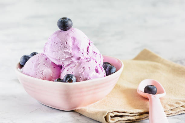 Violet Sweet Ice Cream with Blueberry in Bowl. Three Ball of Ice-Cream with Fruit in Purple Vase. Portion of Frosting Sorbet. Berry in Spoon. Delicious Freezing Dish. Frosting Creamy Dessert stock photo