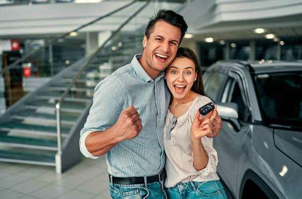 Visiting car dealership. The successful visit to the dealership. Happy young couple chooses and buying a new car for the family. new stock pictures, royalty-free photos & images