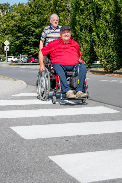 visitor in retirement home pushing senior man on wheelchair - wheelchair street imagens e fotografias de stock