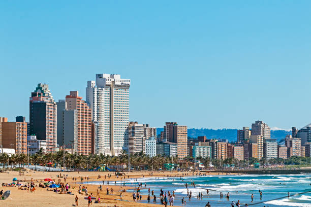 Visitors on beach Agaist City Skyline in Durban DURBAN, SOUTH AFRICA - APRIL 17, 2017: Many morning visitors, swimmers and surfers on the beach against Durban City skyline in South Africa durban stock pictures, royalty-free photos & images