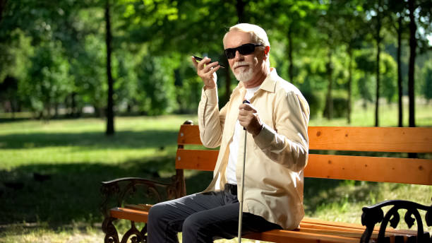 anciano con discapacidad visual usando la aplicación de control por voz en el teléfono inteligente, innovaciones - ceguera fotografías e imágenes de stock