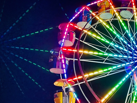 Lens reflection of bright colorful Ferris Wheel lighting, small town summer celebration. Minimalist style of lighted carnival ride, amusement park Ferris Wheel on summer evening. Recreational summertime fun. Ferris Wheel background.