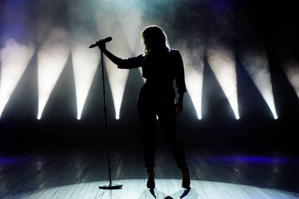 Vocalist singing to microphone. Singer in silhouette stock photo