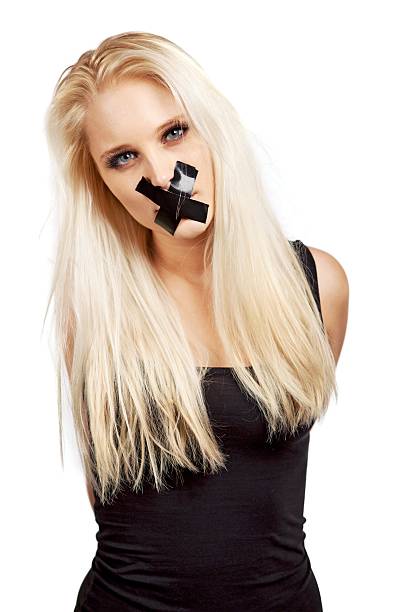 Voiceless Woman in a Struggle for Her Freedom Voiceless woman with a duct tape over her mouth in a struggle for her freedom of expression human mouth gag adhesive tape women stock pictures, royalty-free photos & images