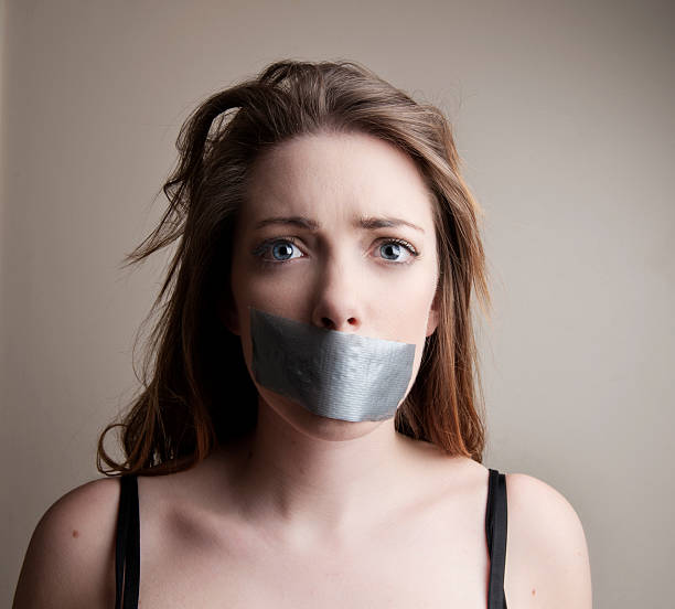 Voiceless Woman Photograph of a young woman with her mouth taped closed human mouth gag adhesive tape women stock pictures, royalty-free photos & images