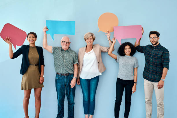 Voicing out our opinions Shot of a diverse group of businesspeople holding up speech bubbles against a blue background waiting in line photos stock pictures, royalty-free photos & images