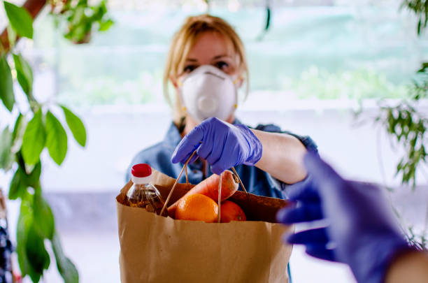 Volunteer Bringing food to old and disability people in quarantine Woman delivering food in paper bag during Corona outbreak.Female volunteer holding groceries in the house porch in COVID-19 outbreak food donation stock pictures, royalty-free photos & images