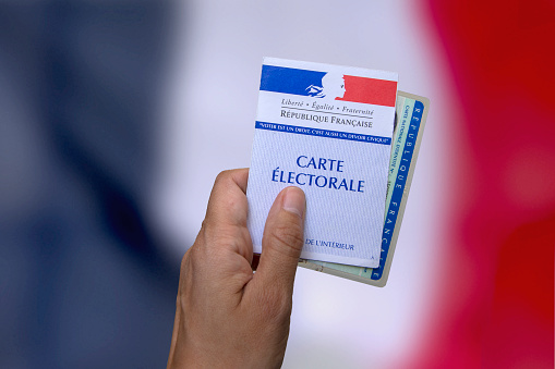 hand who holds an electoral card and an identity card to vote