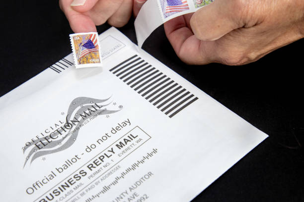 Voter putting a stamp on a mail in ballot stock photo