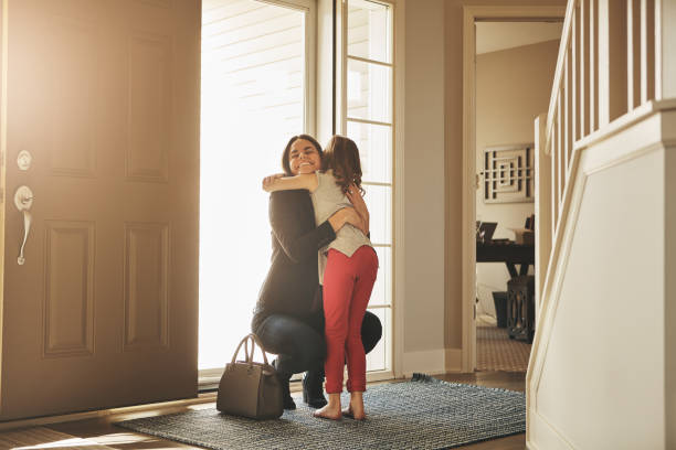 I waited all day for these hugs! Shot of a happy mother arriving home to a loving welcome from her daughter returning home stock pictures, royalty-free photos & images