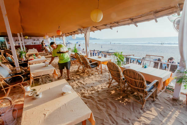 Waiter in beach cafe making service for relaxing tourists on vacation stock photo