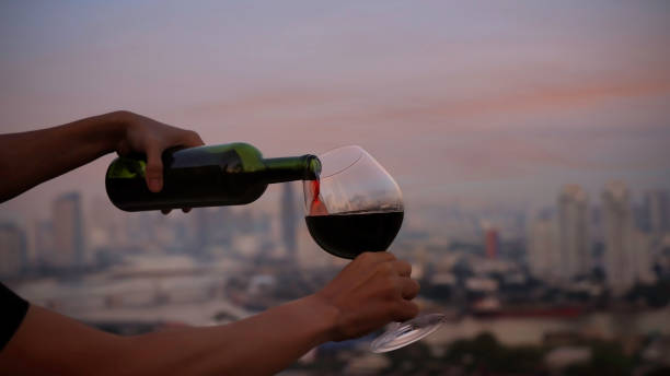 garçom derramando vinho tinto em uma taça no telhado com a cena do céu da cidade e do pôr do sol - serviço de bordo - fotografias e filmes do acervo