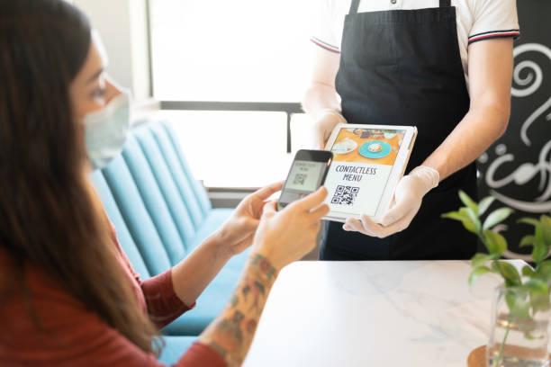 Waiter Showing Contactless Menu To Customer Young woman scanning QR code of contactless menu through smartphone in restaurant QR menu stock pictures, royalty-free photos & images