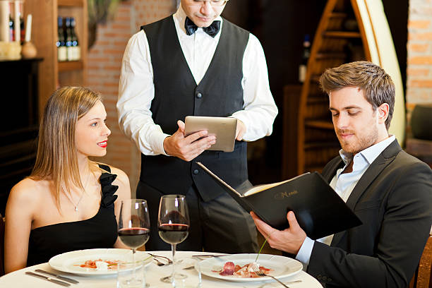 Waiter taking couple's order at a fancy restaurant Waiter taking orders from a couple waiter taking order stock pictures, royalty-free photos & images