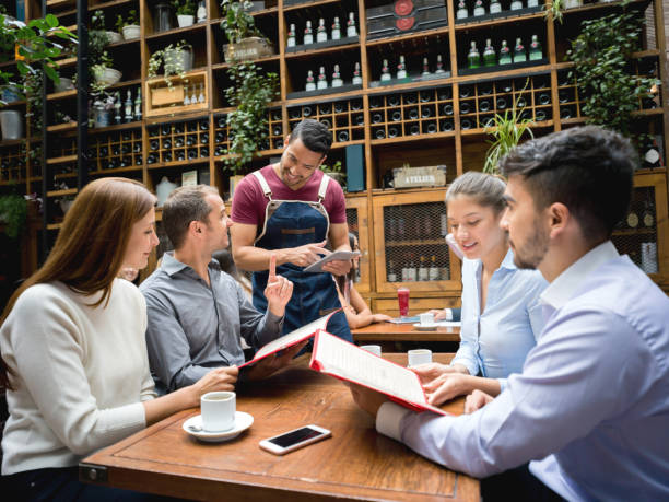 Waiter taking order to a group at a restaurant using a tablet Friendly waiter taking the order to a group of people eating at a restaurant using a tablet computer waiter taking order stock pictures, royalty-free photos & images