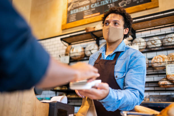 Waitress accepting mobile payment from a customer at bakery stock photo