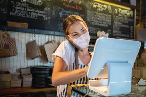 Waitress at a restaurant getting a delivery order on the phone and wearing a facemask Waitress working at a restaurant getting a delivery order on the phone while wearing a facemask - COVID-19 lifestyle concepts waiter taking order stock pictures, royalty-free photos & images