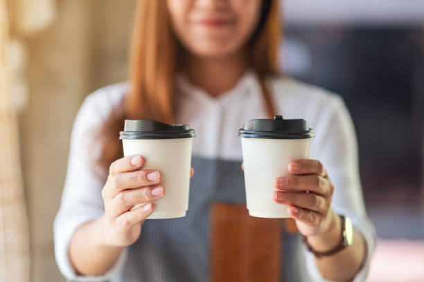 eine kellnerin hält und serviert zwei papiertassen heißen kaffee - hand holding coffee stock-fotos und bilder