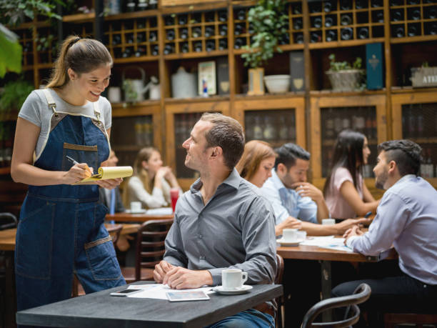 Waitress serving man at a restaurant Happy waitress serving a business man at a restaurant and writing his order on a notepad waiter taking order stock pictures, royalty-free photos & images