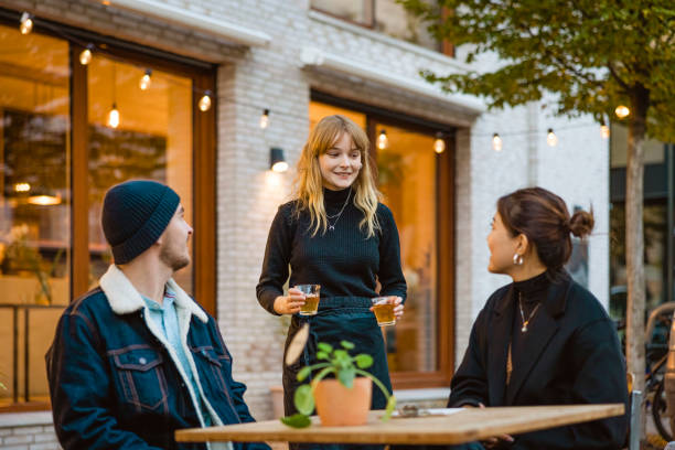 Waitress serving tea to couple sitting at outdoor cafe table stock photo