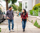 Two friends talking as they walk along a sidewalk in San Francisco's Mission District.